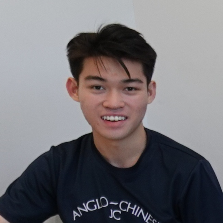 Young man smiling, wearing a navy blue T-shirt with white text.