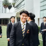 Young students in school uniforms smiling outdoors at Axiom Education.