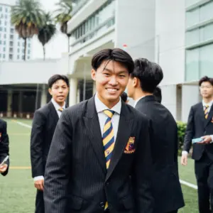 Young students in school uniforms smiling outdoors at Axiom Education.