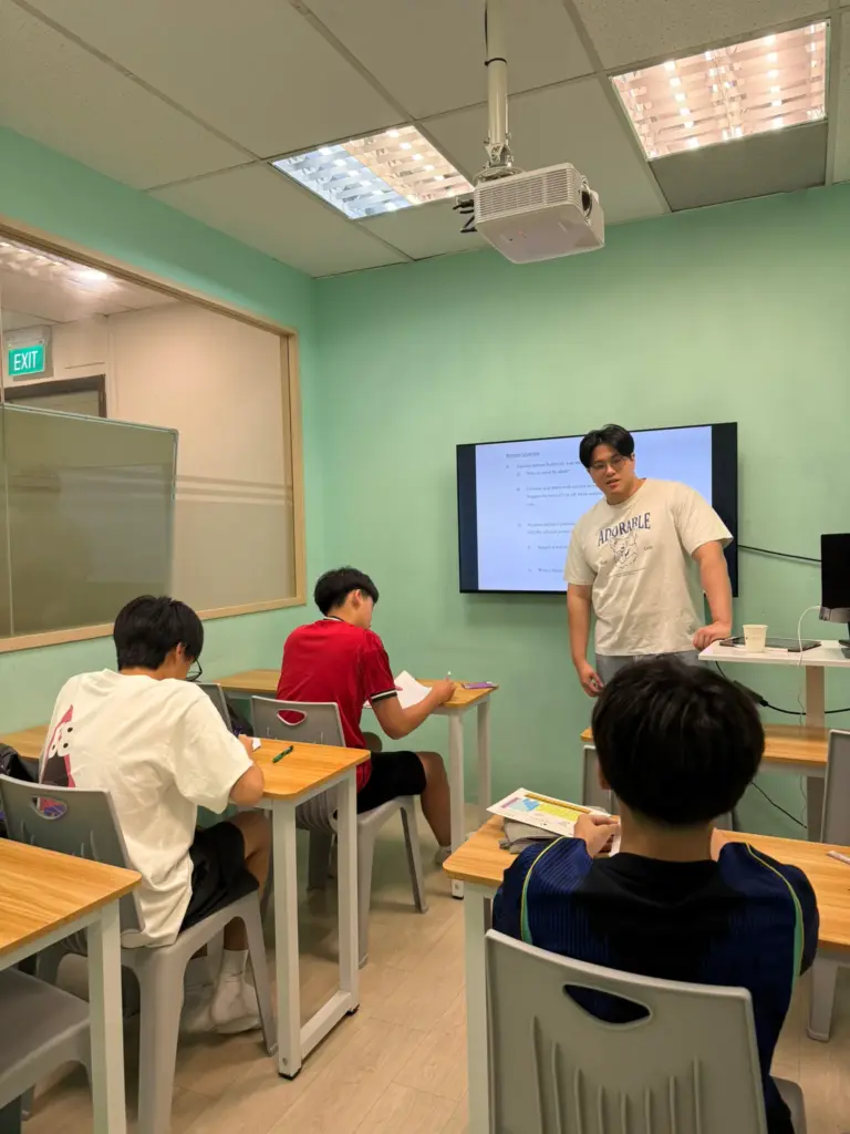 Young teacher explaining math concepts to students in a classroom.