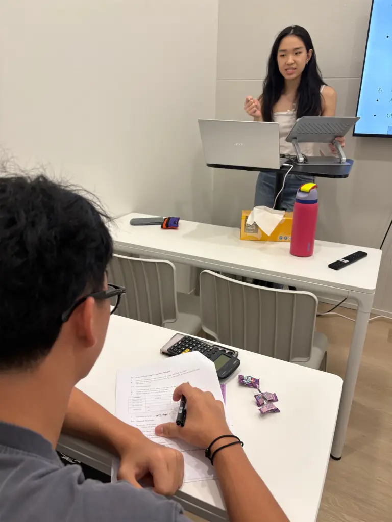 Young woman giving a chemistry lecture in a classroom setting.