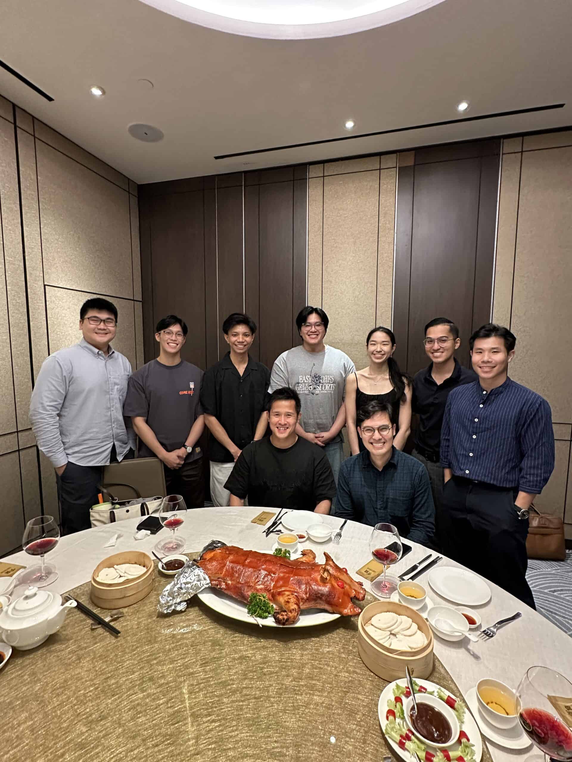 Group of young professionals celebrating with a roasted pig at a dinner event.