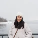 Smiling woman in winter clothing by snowy lake in winter.