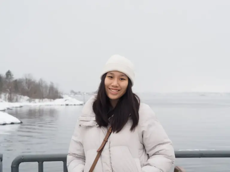 Smiling woman in winter clothing by snowy lake in winter.