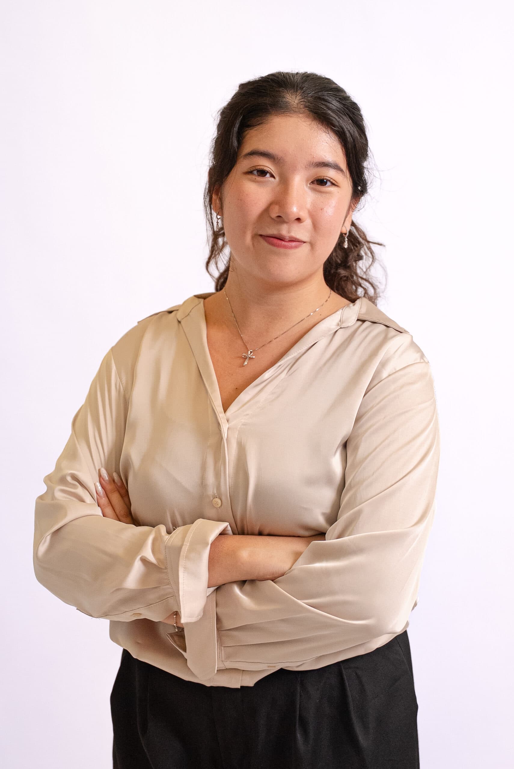 Confident young woman with crossed arms in professional attire.