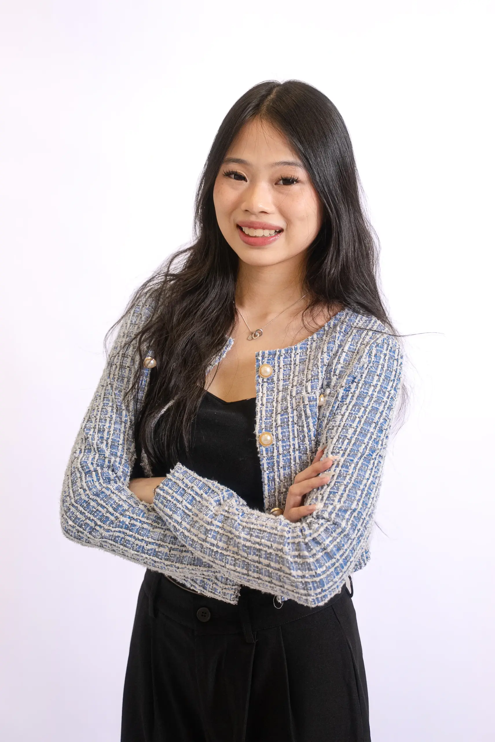 Confident young woman in professional attire with crossed arms.